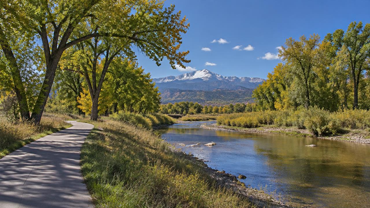 Fountain Creek Regional Park trail and creek in Fountain, Colorado with snow-capped Pikes Peak in the distance